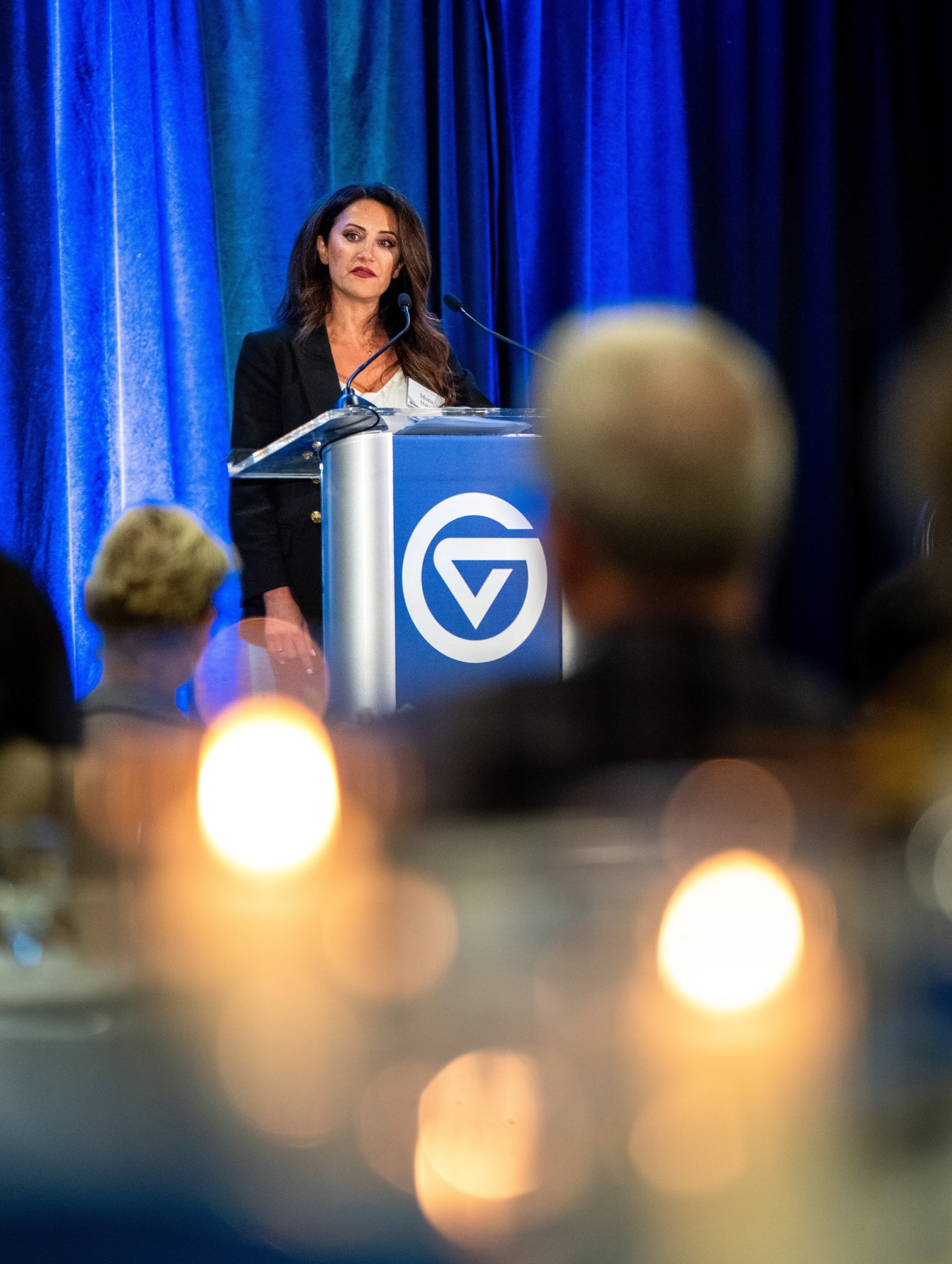 A female speaker at the podium with candles blurry in the foreground